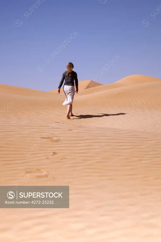 Oman, Empty Quarter. A tourist strides off into the endless dunes.