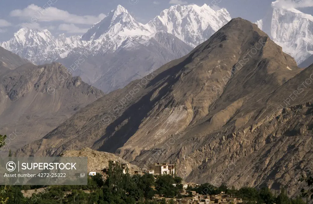 The jagged peaks and bare hills  of the Karakorum Range dominate the skyline of Karimabad.  The Baltit Fort towers over the village.