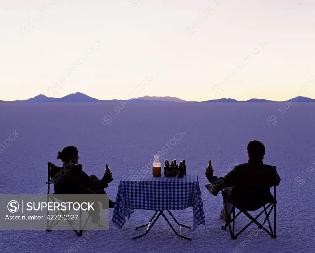 Tourists enjoy sundowners while looking out across the endless salt crust  of the Salar de Uyuni, the largest salt flat in the world at over 12,000  square kilometres.