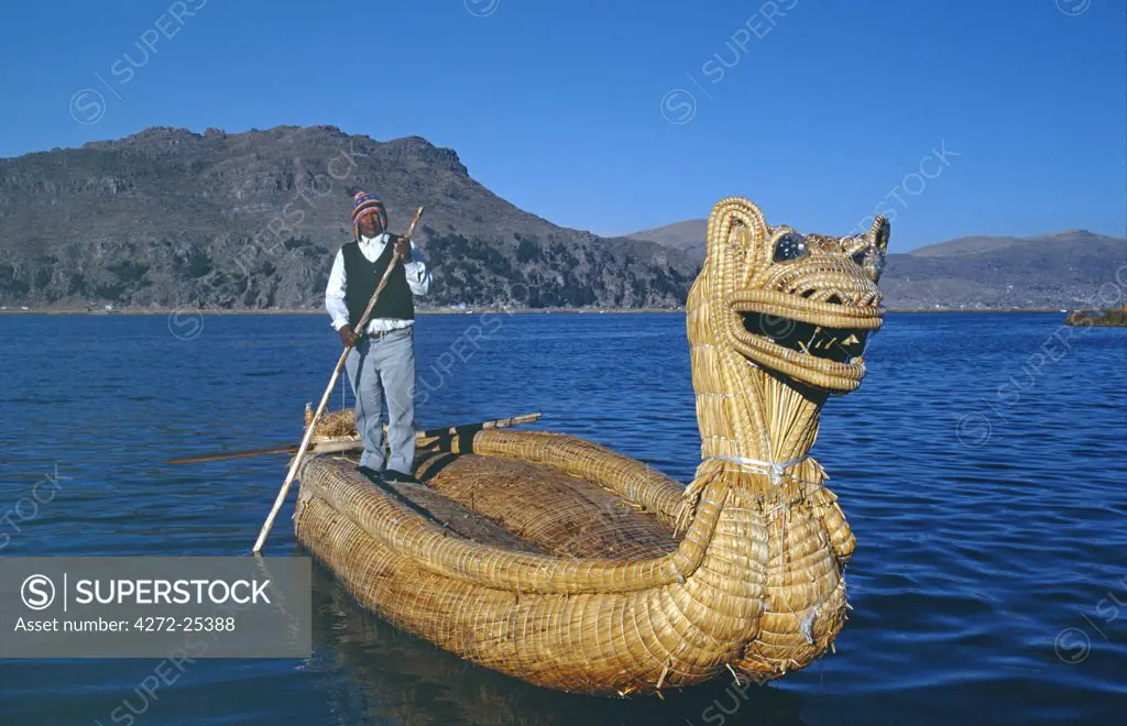 An Indian man from the Uros Islands, islands made from floating reeds, poles his reedboat across Lake Titicaca