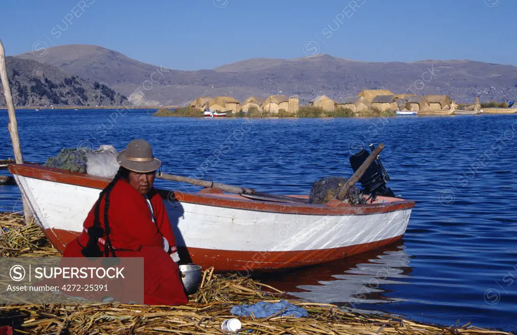 An Indian woman from the Uros or floating reed islands of Lake Titicaca, washes her pans in the water of the lake