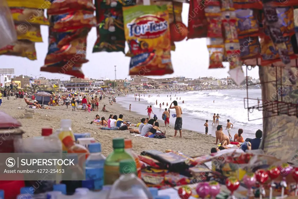 Summer crowds descend on the beach town of Huanchaco, in northern Peru - framed by a beachside snack stall. Huanchaco is famous for its fishermen who ride the surf on traditional totora (reed) boats.