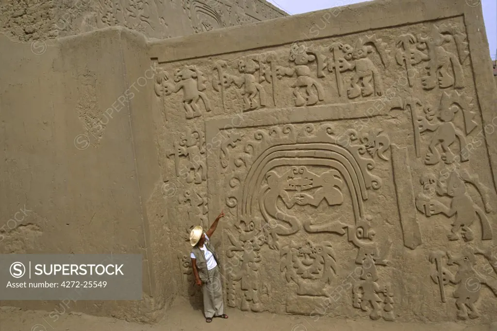 A tour guide explains the bas relief designs carved into the adobe walls of the Huaca Arco Iris (Rainbow Temple), near Trujillo in northern Peru. The site is from the Chimu period between AD 850 and 1470.