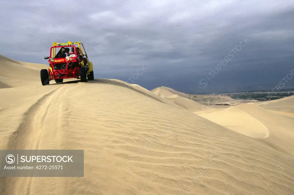 A dune buggy on the sand dunes bordering the city of Ica, in southern Peru