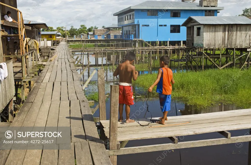 Peru, Amazon River. Boys fishing off the stilted walkway in the village of Islandia.