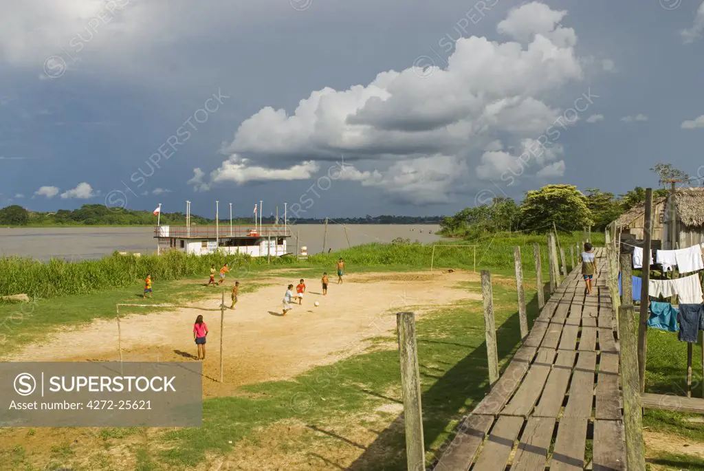 Peru, Amazon River. Family playing football in the village of Islandia.