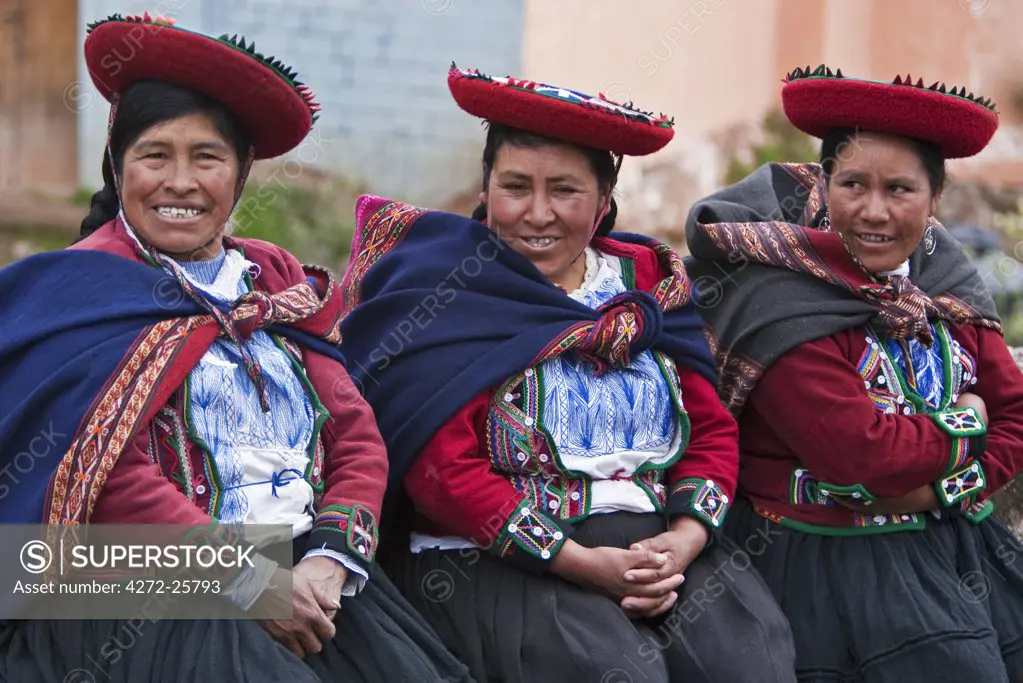 Peru, A group of native Indian women in traditional costume wearing saucer-shaped hats, beautifully decorated red jackets and woollen blankets round their shoulders.