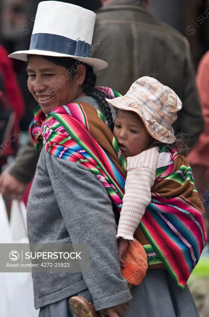 Peru, A Peruvian woman with her child slung on her back shops at Santuranticuy market, held in Cusco on Christmas Eve every year.