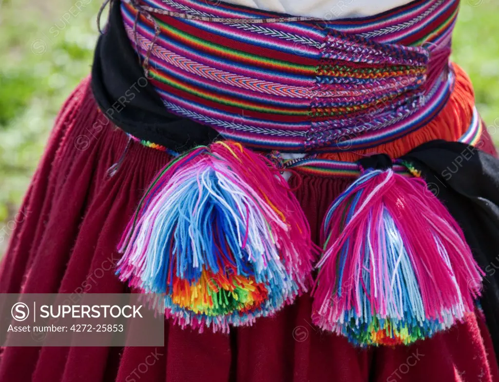 Peru, The beautifully woven belt of a Quechua-speaking woman on Taquile Island from which hang woolly pompoms.