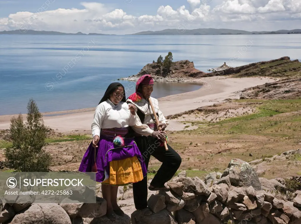 Peru, A Quechua-speaking man plays his flute on Taquile Island while his wife spins wool.
