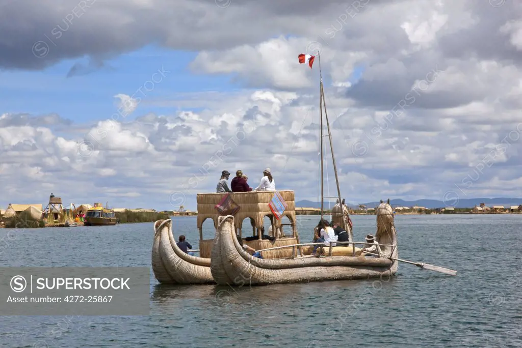 Peru, A large reed boat used by tourists is rowed down the main channel between the unique floating islands of Uros on Lake Titicaca.