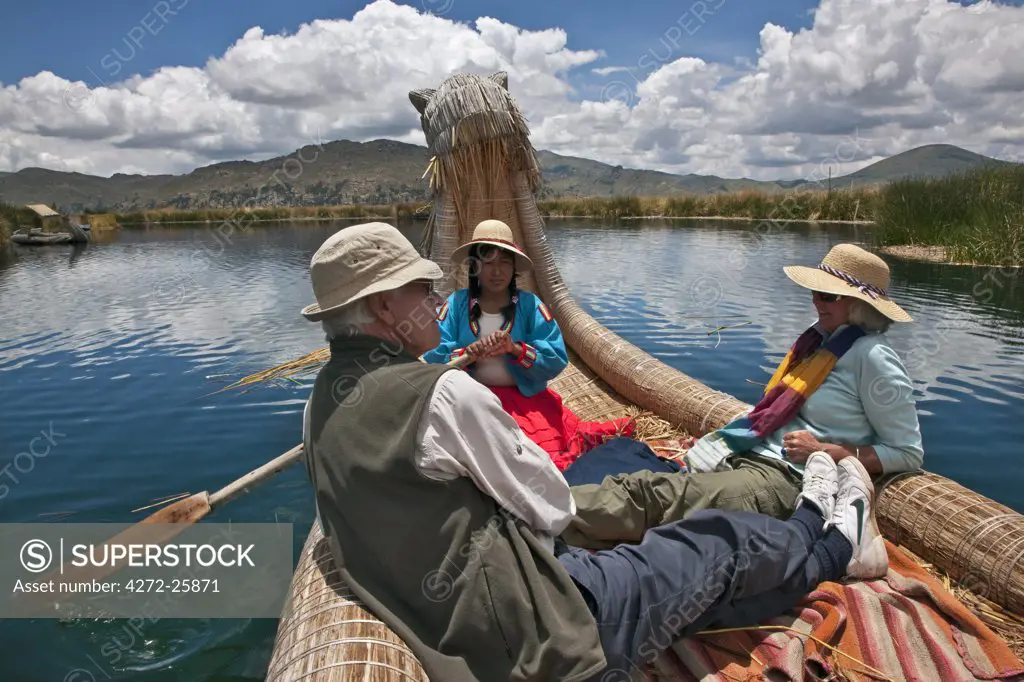 Peru, Tourists being rowed in a traditional reed boat around the unique floating islands of Uros on Lake Titicaca.