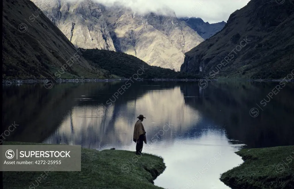 A high lake in the Vilcabamba range; at the waters edge a mule wrangler checks his fishing line at dawn.