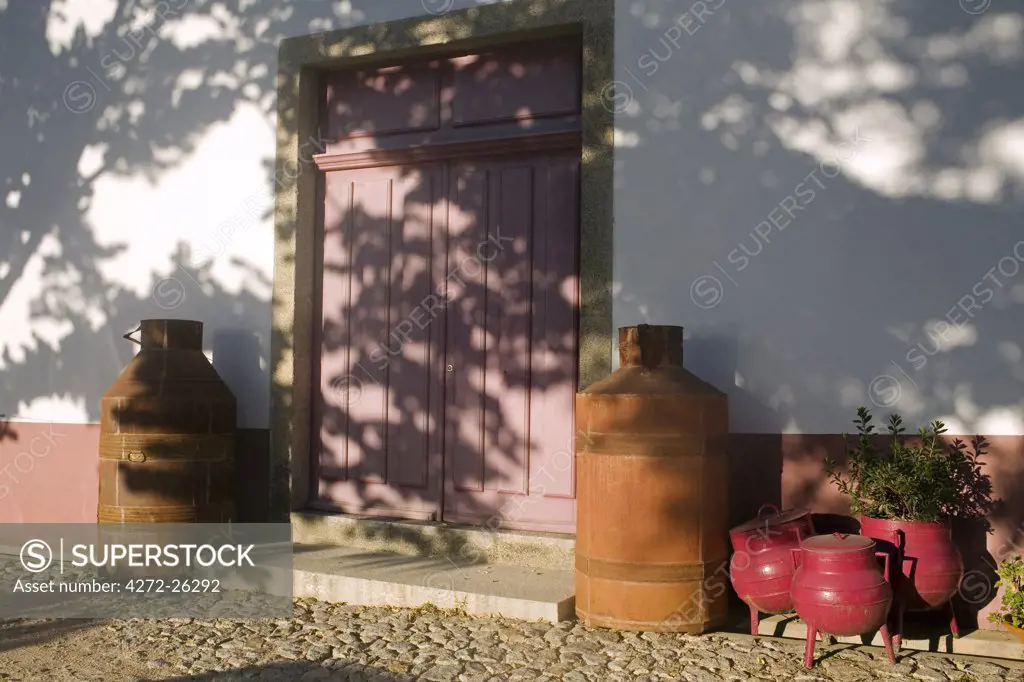Portugal, Douro Valley, Pinhao. The sun sets on outbuildings of the Quinta Nova de Nossa Senhora do Carmo estate in the Douro valley in Northern Portugal. The bright pink pots in the foreground are traditional Portuguese oven wear used traditionally to cook food on wood fires.