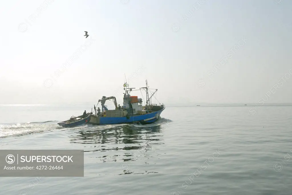 Fishing boat in a foggy morning going to the sea. Setubal, Portugal
