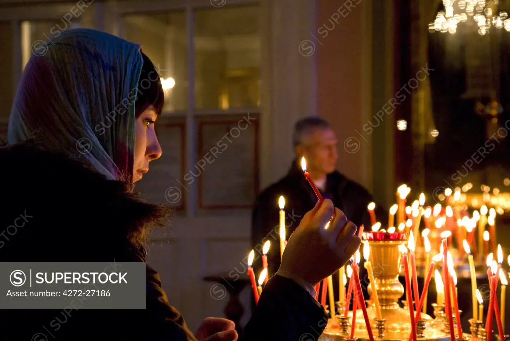 Russia, St.Petersburg; A girl lighting a candle just before the Orthodox ceremony at Vladimirsky Cathedral