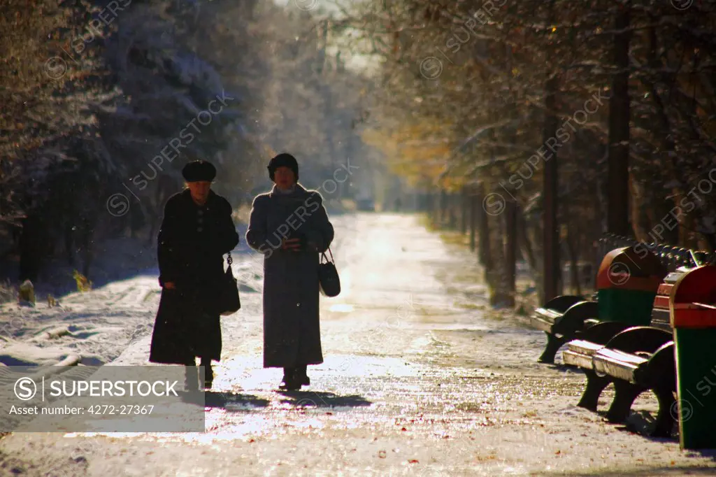 Russia, Far East, Sakhalin; Yuzhno-Sakhalinsk; Two elderly woman walking amidst trees in the main park of the city