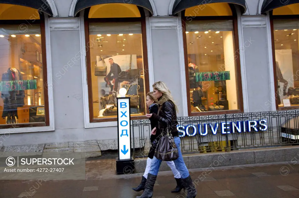 Russia, St. Petersburg; Two Russian girls walking along Nevski Prospekt in front of shops
