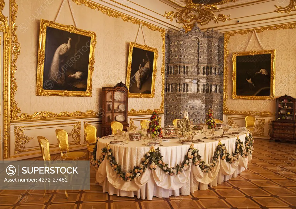 Russia, St Petersburg, Catherine Palace, Tsarskoe Selo.  The Cavaliers' Dining Room.  The table is laid for Tsarina Elizabeth's gentlemen-in-waiting, in the refined gold and white  room created by Rastrelli.