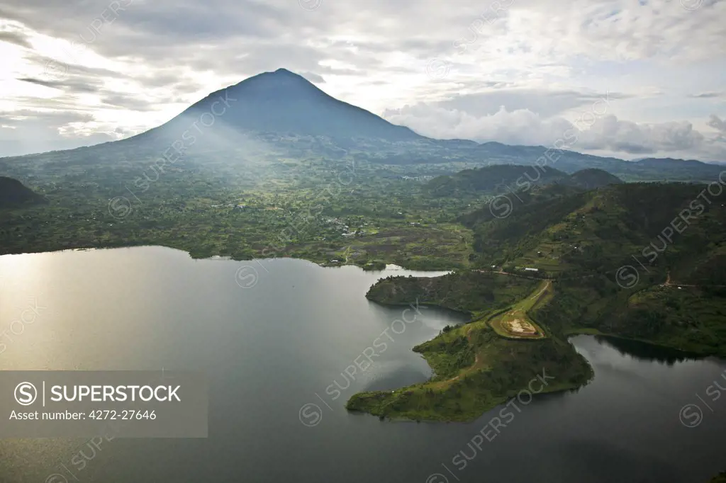Rwanda. Lake Burero reaches out underneath the volcanoes. The volcanic lakes provide protected habitat for numerous species of birds.