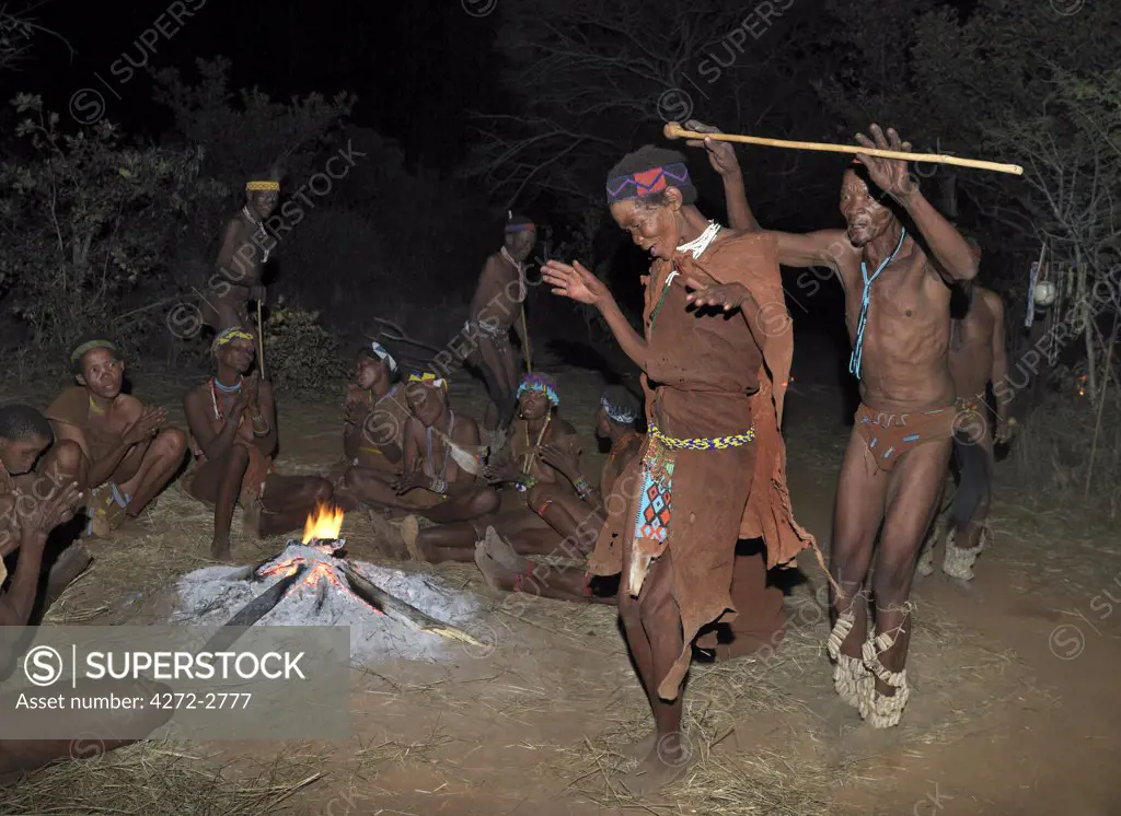 A man and wife of a San community dance during a sing-song round their campfire.  The men have rattles wound round their legs to help the rest of them keep rhythm during their dances. These N!!S hunter gatherers live in the Xai Xai Hills close to the Namibian border. Their traditional way of life is fast disappearing.