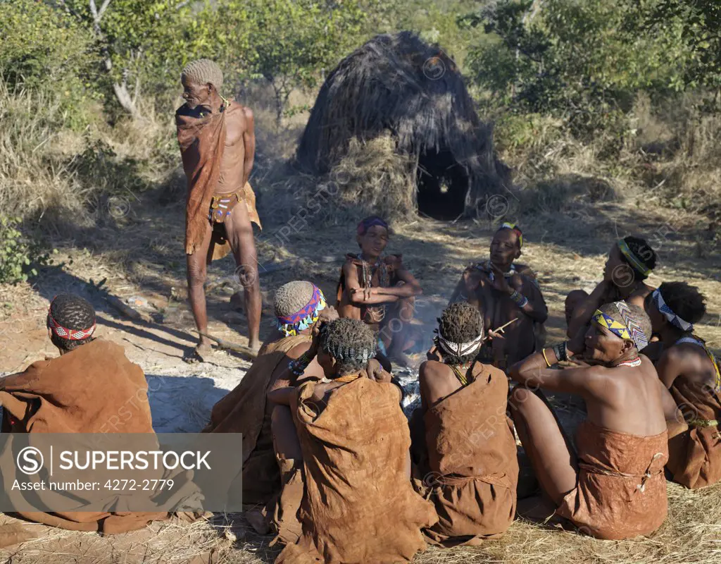 A group of NS hunter gatherers sit round their fire and smoke. They are a part of the San people, often referred to as Bushmen. They differ in appearance from the rest of black Africa having yellowish skin and being lightly boned, lean and muscular. The NS live in the harsh environment of a vast expanse of flat sand and bush scrub country straddling the Namibia Botswana border.