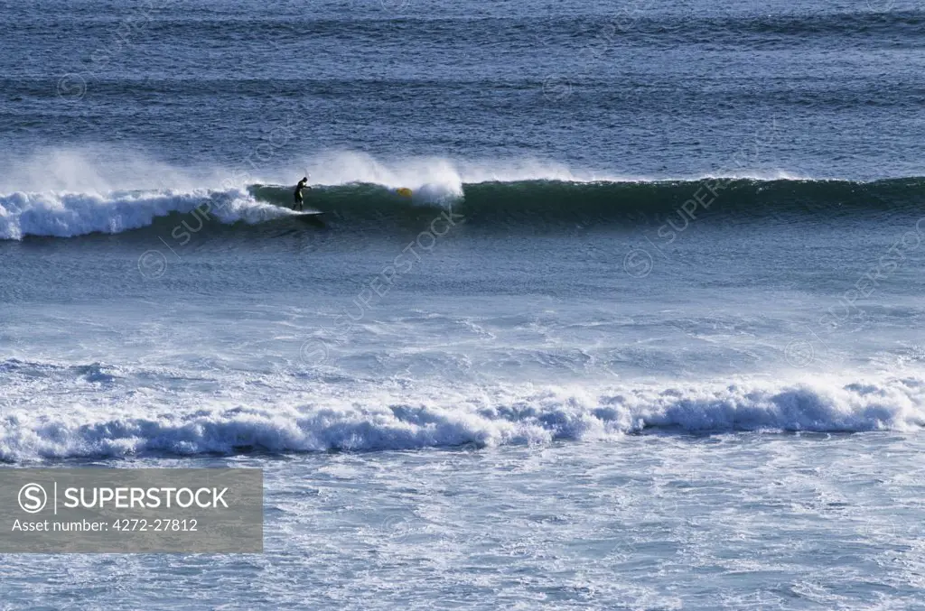 Surfer rides a wave on the wild Atlantic coast south of Kommetjie
