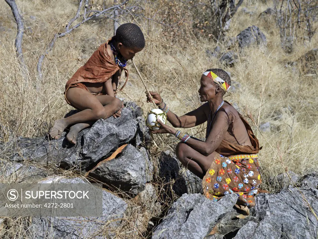 A NS boy quenches his thirst by sucking water through a hollow reed from water carried in a blown ostrich egg by his mother. The NS live in the harsh environment of a vast expanse of flat sand and bush scrub country straddling the Namibia Botswana border.