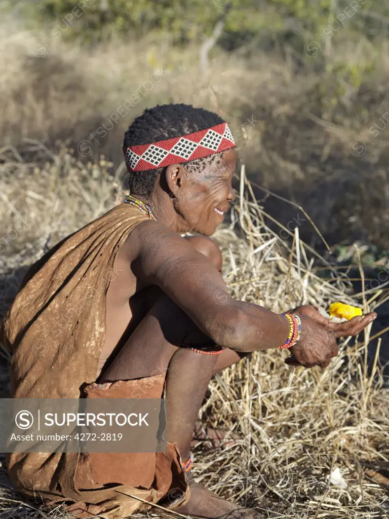 A woman of the NS hunter gatherer community enjoys the yoke of an ostrich egg, which has been baked in the embers of a fire. The NS live in the harsh environment of a vast expanse of flat sand and bush scrub country straddling the Namibia Botswana border.