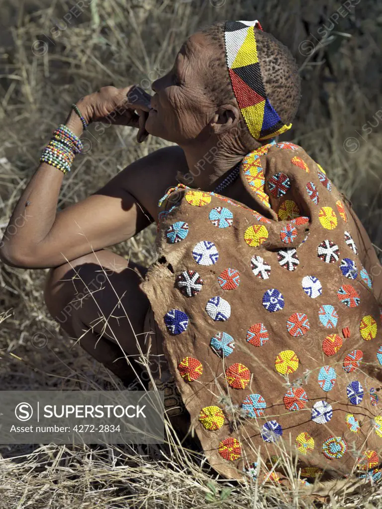 A beautifully decorated leather cape worn by a woman from the NS hunte gatherer band. She has a small tortoise shell as part of her adornments. The NS live in the harsh environment of a vast expanse of flat sand and bush scrub country straddling the Namibia Botswana border.