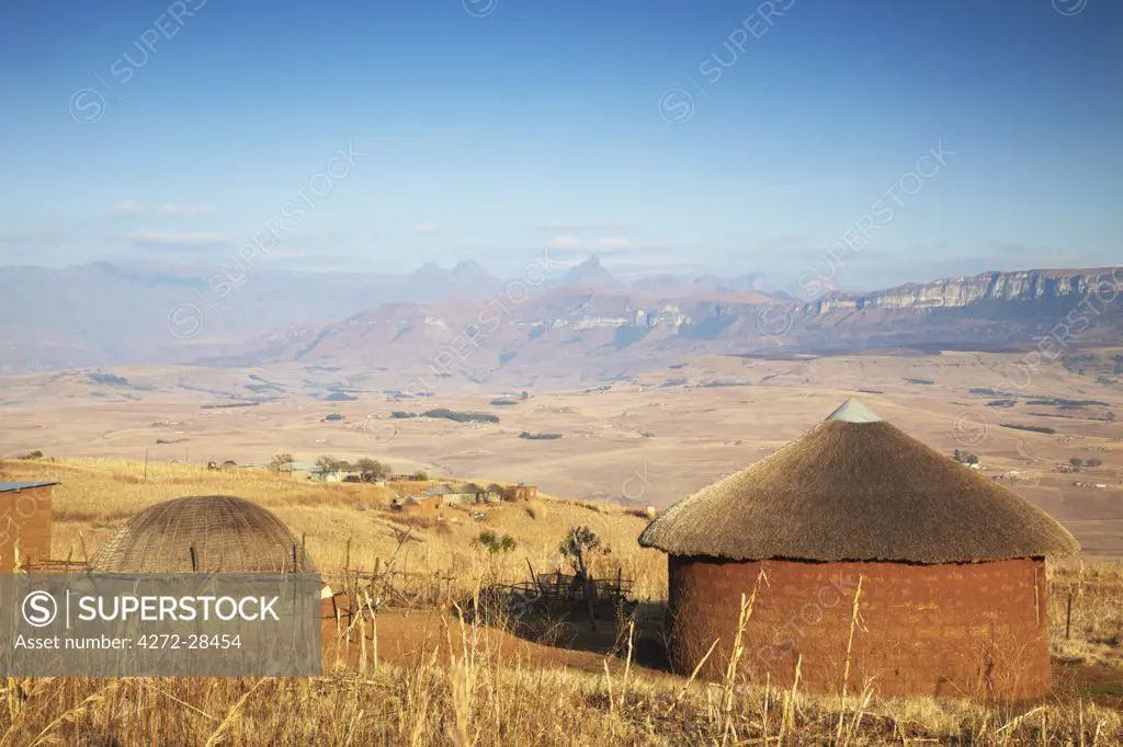 Village huts with Cathedral Peak in background, Ukhahlamba-Drakensberg Park, KwaZulu-Natal, South Africa