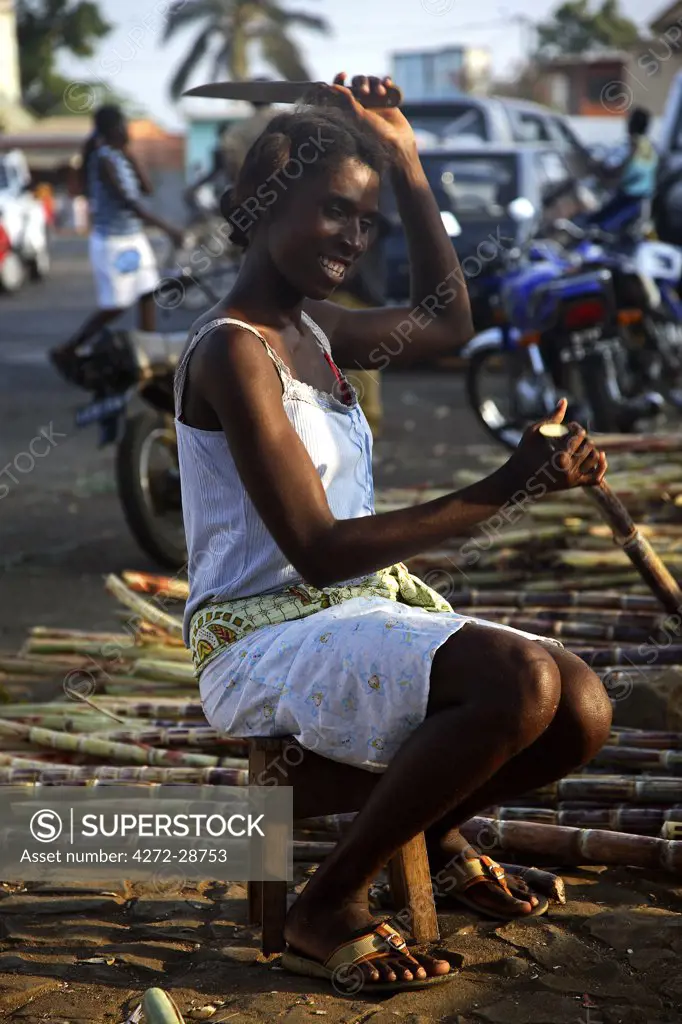 A Sao Tomense woman strips the outer skin of a piece of sugar cane in the market of Sao Tome. It is common to chew on the sugar cane, especially for children. Sugarcane was once a major export in the first half 17th century. Sao Tome were at this time the largest exporters in the world.