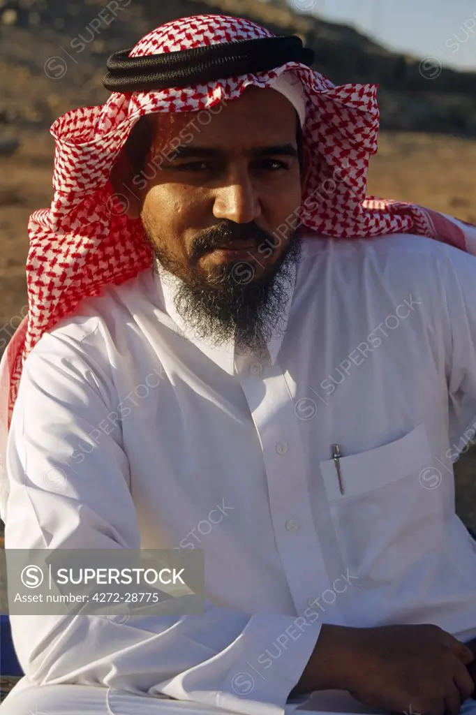 Saudi Arabia.  A Saudi man wearing his traditional clothes - a white cotton thawb with a headress comprising a white tagia (a skullcap) and a ghutra (red-checked square of cloth) held in place with an iqal (doubled black cord).