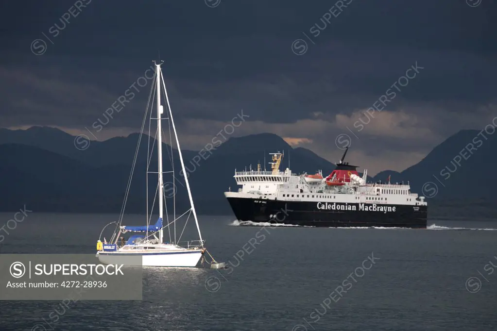 Scotland, Isle of Mull. A ferry passing a moored yacht in the Sound of Mull enroute to Tobermory on the Isle of Mull.