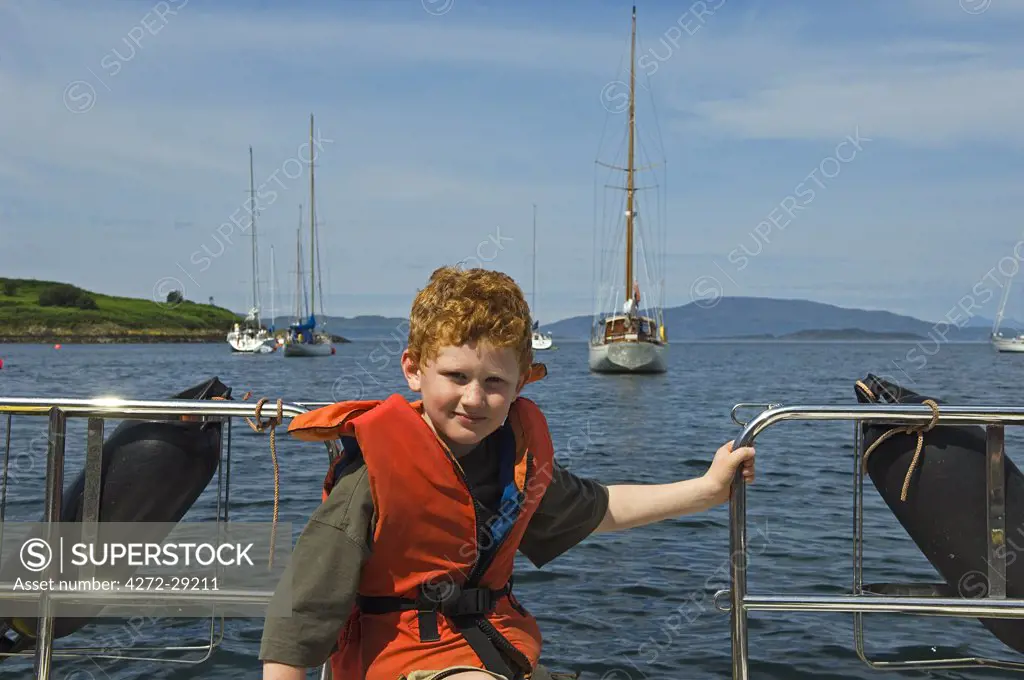A boy relaxes on a boat at Crinan on the west coast of Scotland