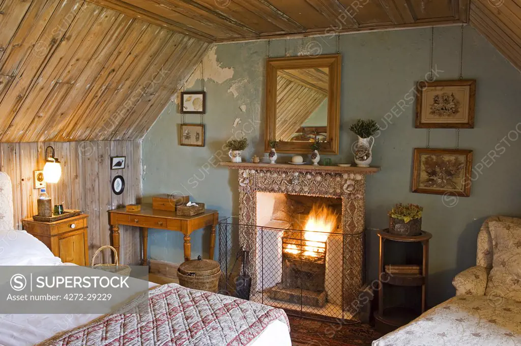 A shell encrusted fireplace typifies the rustic chic of one of the bedrooms in GlenBatrick Lodge.  The lodge overlooks the white sandy shore of Loch Tarbert on the west side of Jura.  Beautifully isolated the lodge is only accessible by boat or a five hour walk.