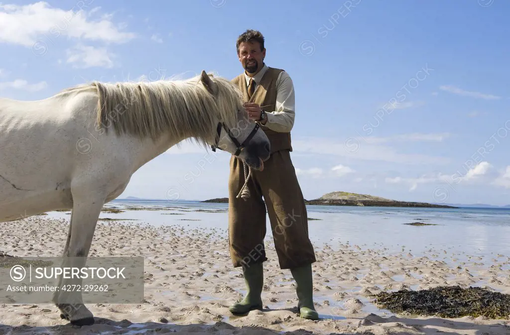 Gordon Muir, stalker and ghillie at Glen Batrick Lodge, leads a stalking pony onto the beach of Loch Tarbert
