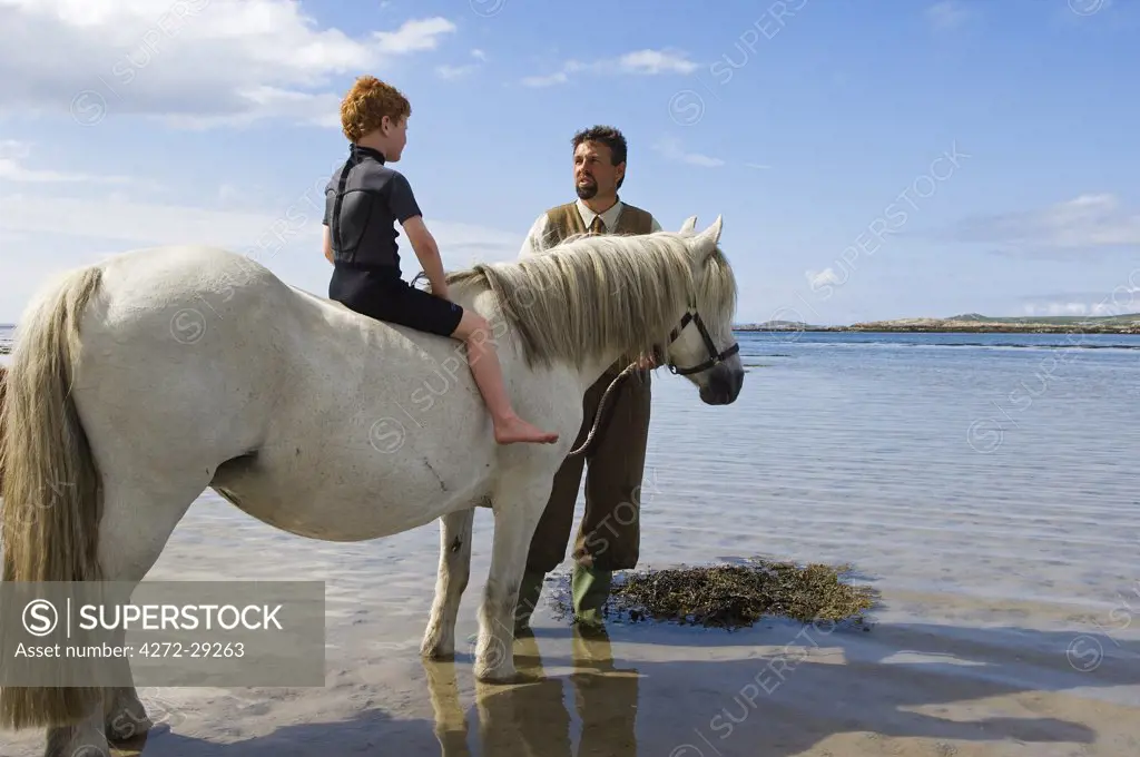 Gordon Muir, stalker and ghillie at Glen Batrick Lodge, leads young guest from the lodge along the shore of Loch Tarbert on a Highland pony