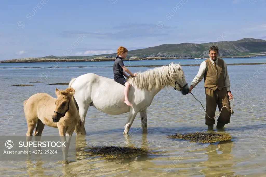 Gordon Muir, stalker and ghillie at Glen Batrick Lodge, leads young guest from the lodge along the shore of Loch Tarbert on a Highland pony