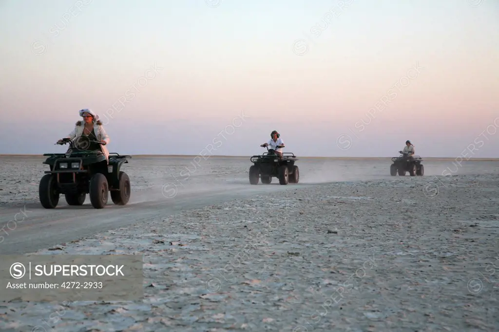 Botswana, Makgadikgadi, Jack's Camp. Tourists race across the pans on quadbikes at sunset.