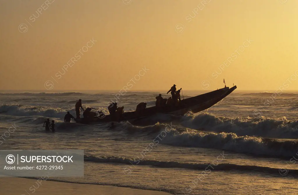 Fishermen launch their boat into the Atlantic Ocean at sunset