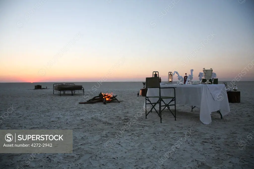 Botswana, Makgadikgadi. A romantic dinner for two is set up at sunset on the empty Makgadikgadi saltpans.