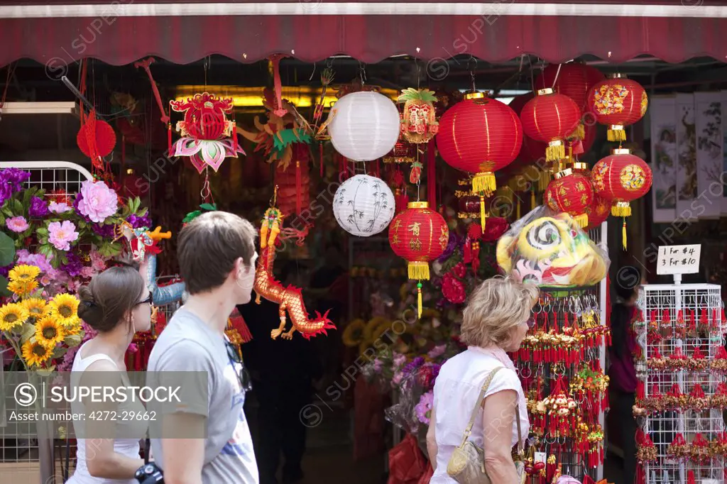 Singapore, Singapore, Chinatown.  Tourists walk past Chinese New Year decorations for sale on Temple Street.