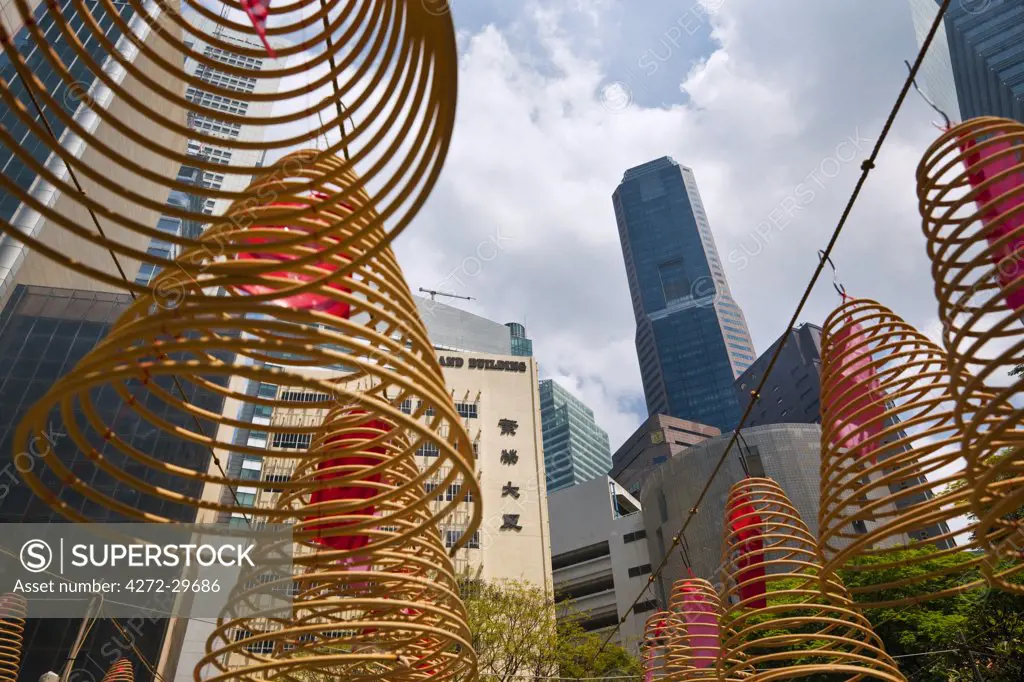 Singapore, Singapore, Raffles Place.  Spiral incense coils with city skyline in background at Wak Hai Cheng Bio Temple.