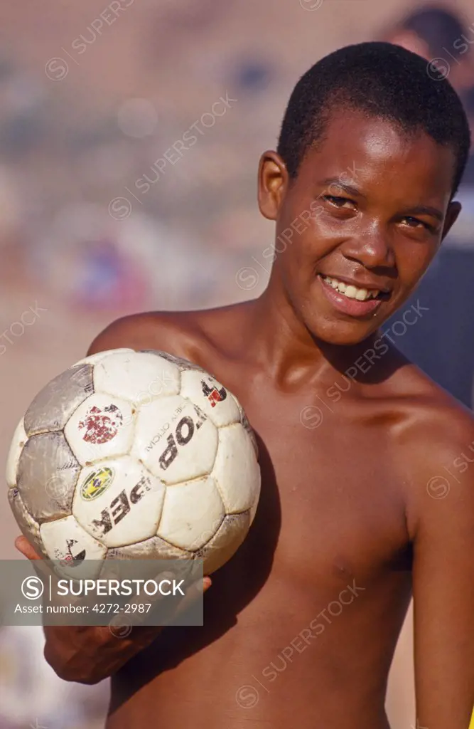 A boy holds his football outside his home in a favela in Sao Paulo.