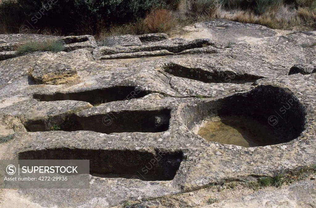 Ancient graves carved out of the solid rock lie alongside circular pits used for tramping grapes beside the small chapel of Santa Maria de la Piscina in the countryside near Pecina