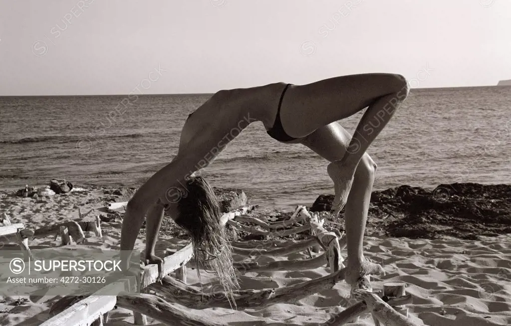 Model doing yoga on the beach a Bridge or wheel Chakarasana