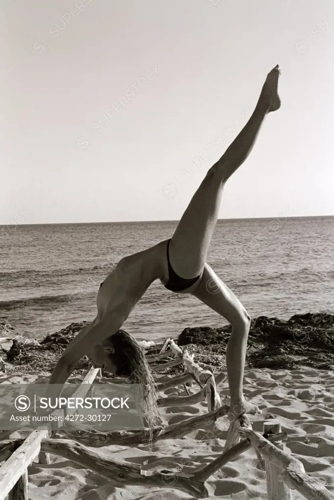 Model doing yoga on the beach a Bridge or wheel Chakarasana