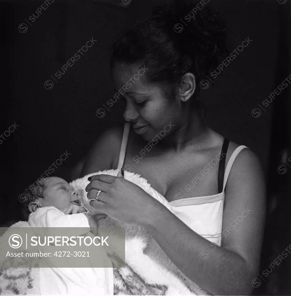 A young mother, called Eliane, holds her new born son while on the doorstep of her home in the favela 'Jardim Colombo' in Sao Paulo Brazil