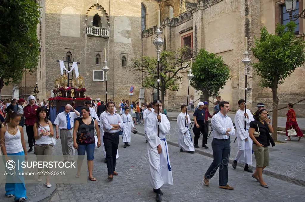 Spain, Andalucia, Seville. Acolytes carry candles through the streets during a procession by one of the Catholic brotherhoods of Seville.
